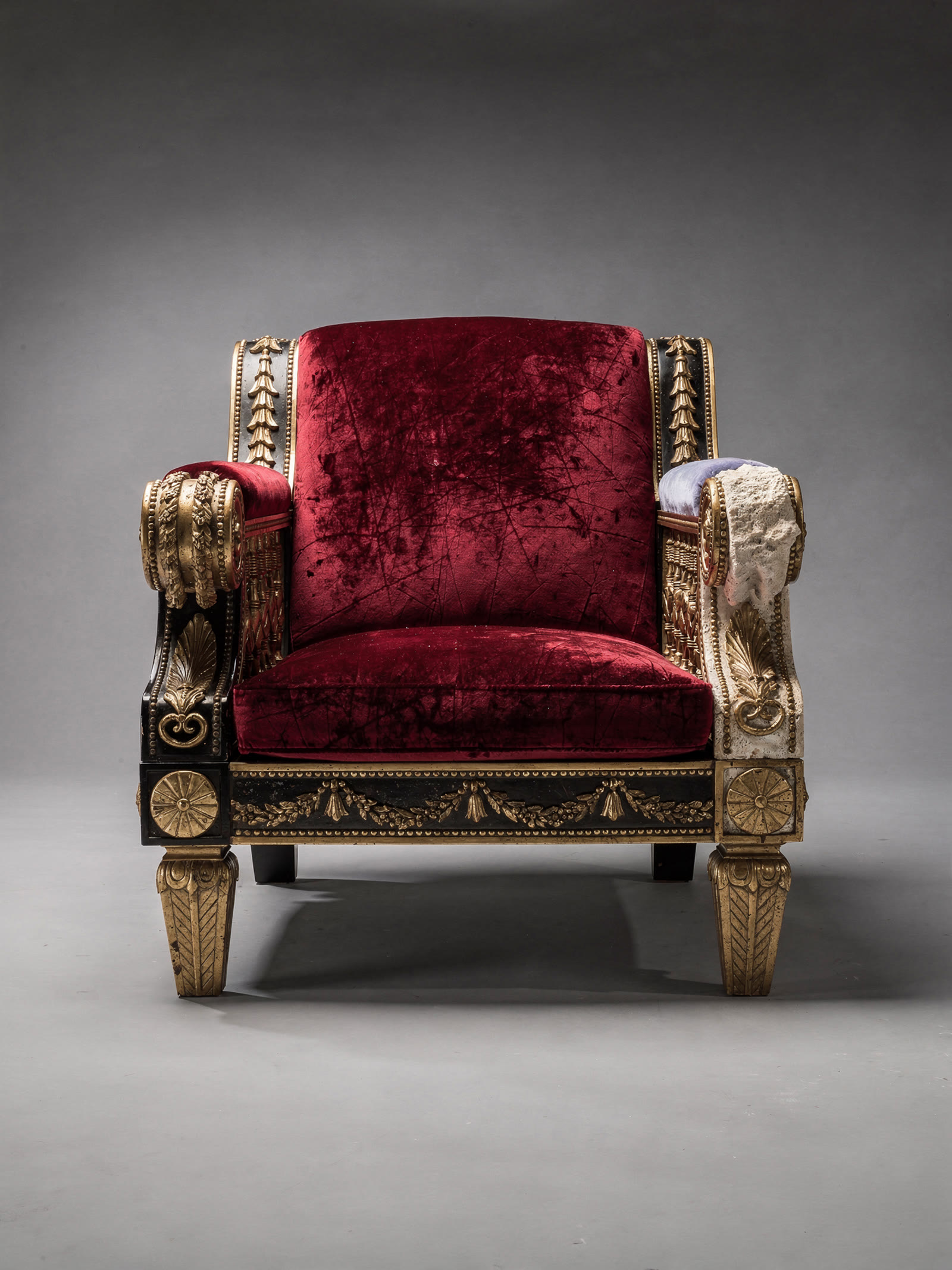 FLUX.2 output for the subject a lounge chair: a black lacquer and gilt armchair in crushed oxblood velvet with one stone arm and a periwinkle drape, on the same grey sweep